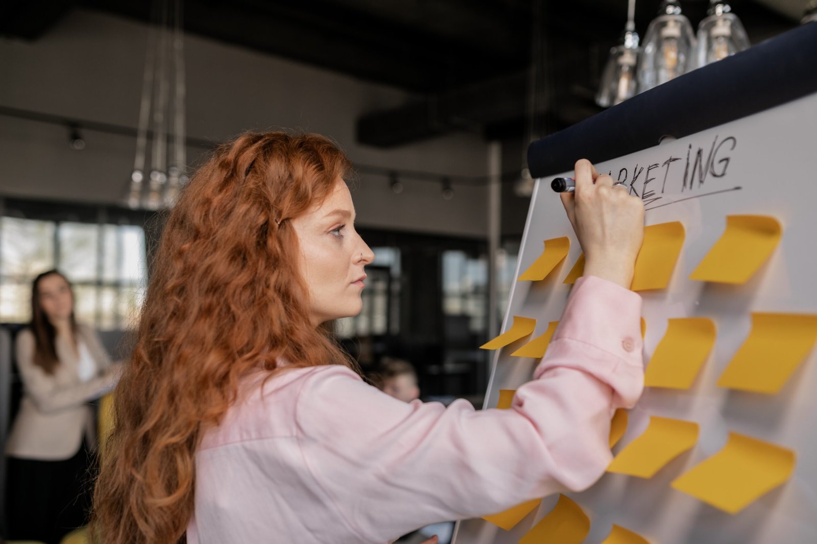 woman-writing-on-a-whiteboard-with-sticky-notes